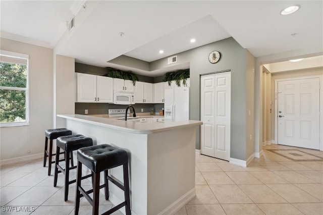 kitchen with a kitchen bar, white appliances, light tile patterned floors, and visible vents