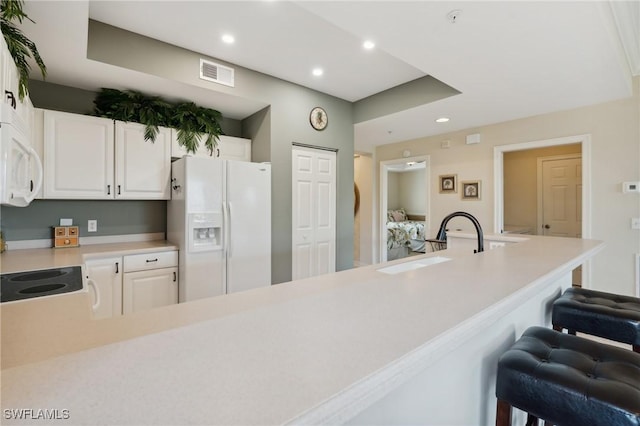 kitchen with visible vents, a breakfast bar, light countertops, recessed lighting, and white appliances