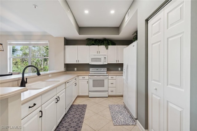 kitchen featuring visible vents, light tile patterned flooring, white cabinets, white appliances, and a sink