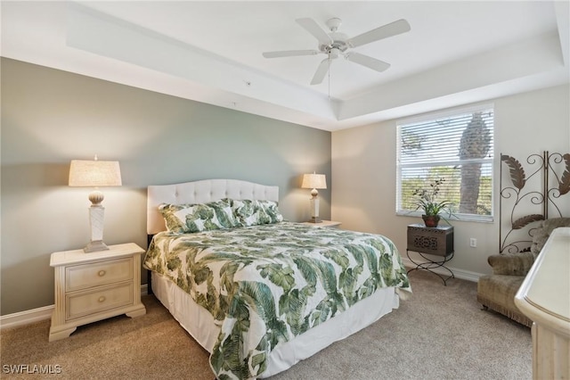 bedroom featuring ceiling fan, light colored carpet, and a tray ceiling