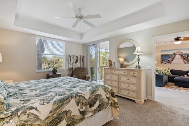 bedroom featuring a raised ceiling, light colored carpet, and access to outside