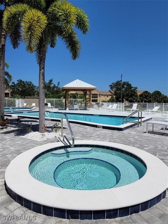 community pool with a patio, a gazebo, fence, and a community hot tub