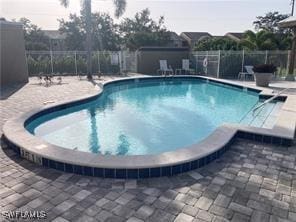 community pool with a patio and fence