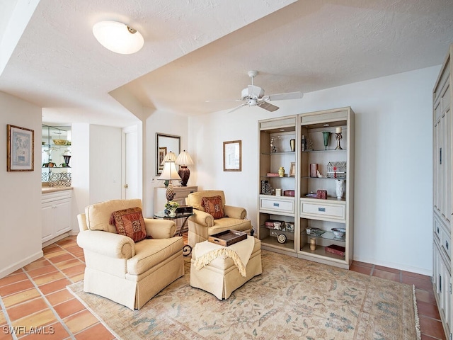 living area with a textured ceiling, ceiling fan, and light tile patterned flooring