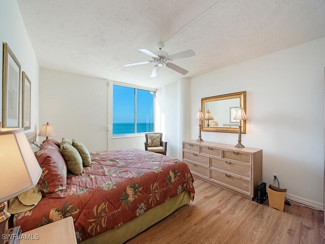 bedroom featuring floor to ceiling windows, ceiling fan, light hardwood / wood-style floors, and a textured ceiling