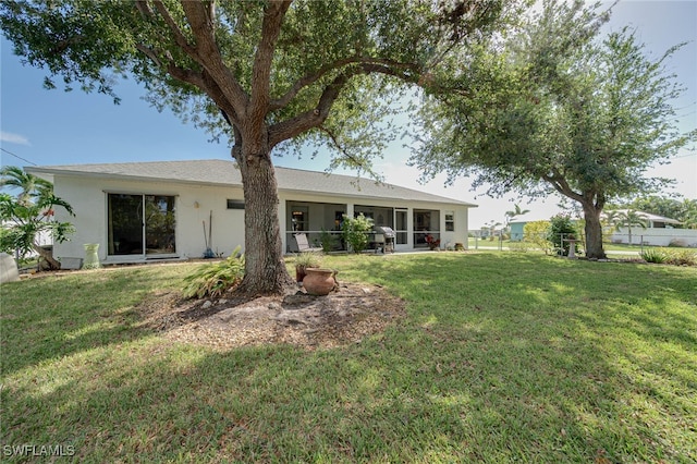 rear view of house featuring a lawn and a sunroom