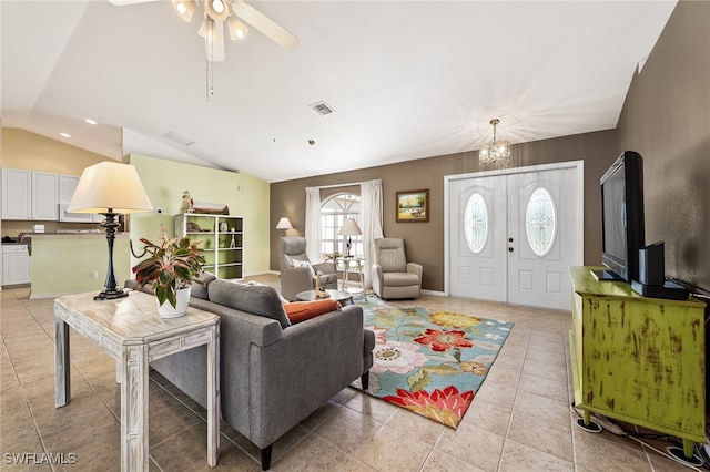 tiled living room with ceiling fan with notable chandelier and vaulted ceiling