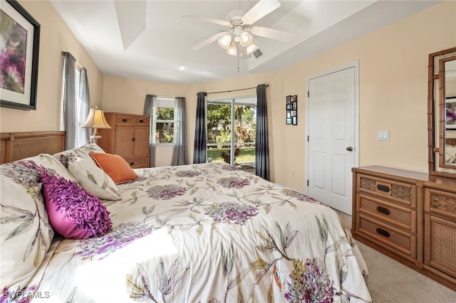 carpeted bedroom with a raised ceiling, access to exterior, and ceiling fan