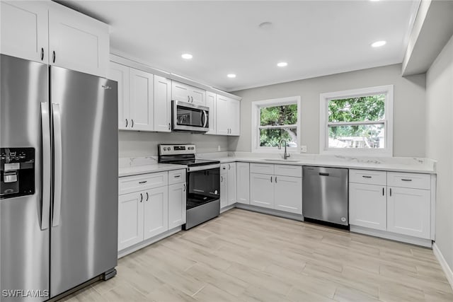 kitchen with sink, light stone counters, white cabinetry, and stainless steel appliances