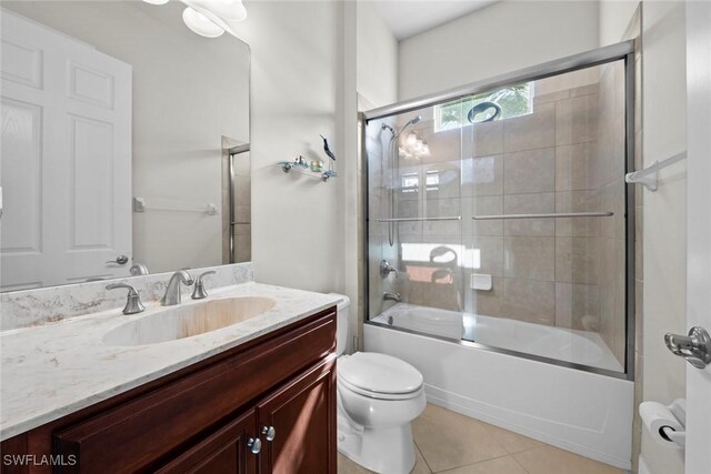 full bathroom featuring shower / bath combination with glass door, tile patterned floors, vanity, and toilet