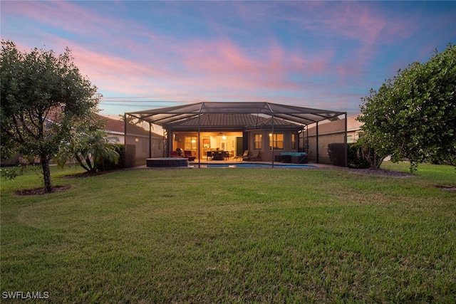 back house at dusk with a lanai, a patio area, a yard, and an outdoor hangout area