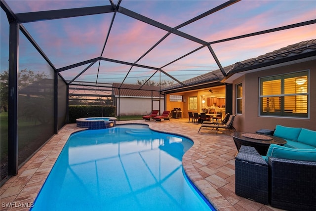 pool at dusk featuring an outdoor hangout area, a patio, ceiling fan, and a lanai