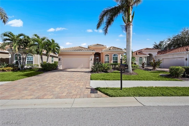 mediterranean / spanish home featuring a garage and a front lawn