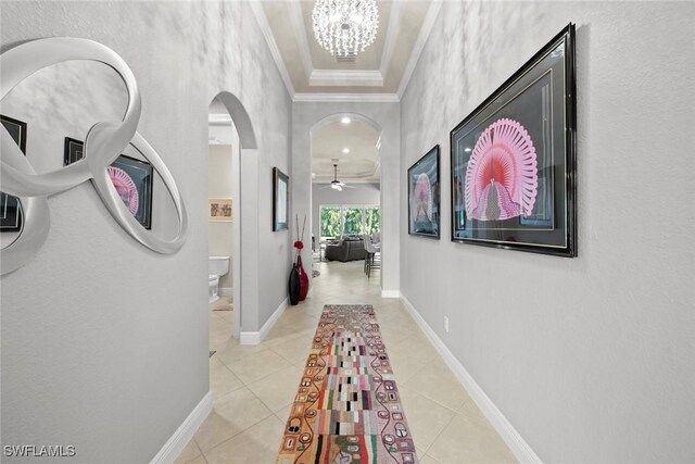 corridor featuring crown molding, light tile patterned floors, and a notable chandelier