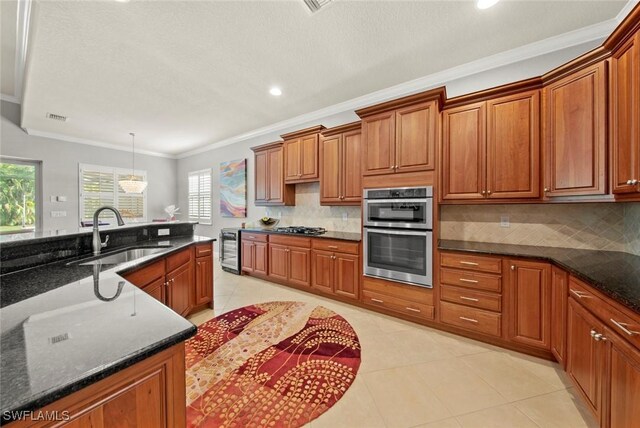 kitchen featuring dark stone countertops, sink, stainless steel appliances, and ornamental molding