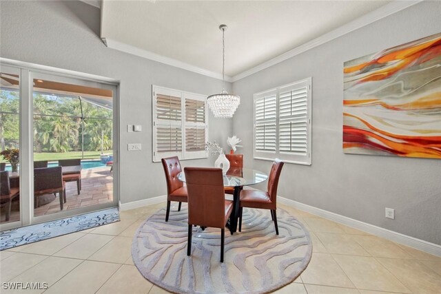 tiled dining space with a notable chandelier, a healthy amount of sunlight, and ornamental molding