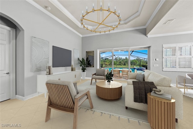 living room with a chandelier, a high ceiling, ornamental molding, light tile patterned floors, and a raised ceiling