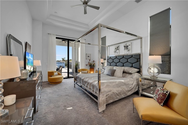 carpeted bedroom featuring access to outside, ceiling fan, and a tray ceiling