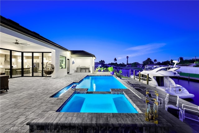 pool at dusk featuring an in ground hot tub, a patio, an outdoor bar, and ceiling fan