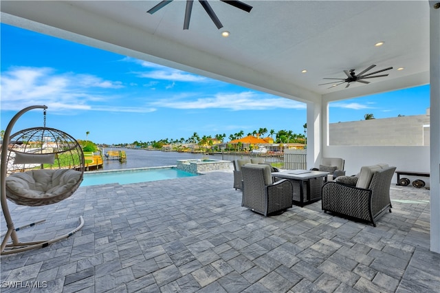 view of patio / terrace featuring an in ground hot tub, a water view, and ceiling fan