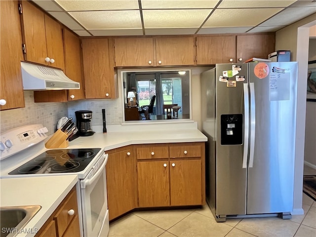 kitchen featuring electric range, a drop ceiling, stainless steel fridge, and exhaust hood