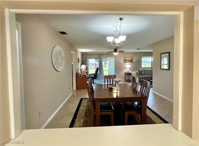 tiled dining room featuring ceiling fan with notable chandelier