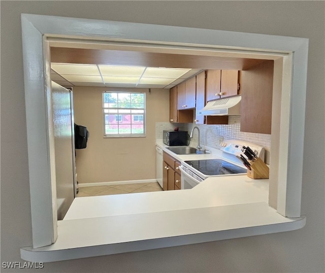 kitchen with decorative backsplash, a paneled ceiling, white appliances, sink, and light tile patterned floors