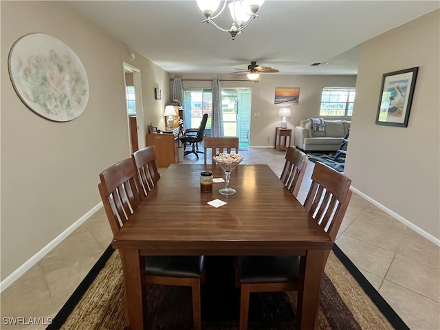 dining space with light tile patterned floors, ceiling fan with notable chandelier, and a healthy amount of sunlight