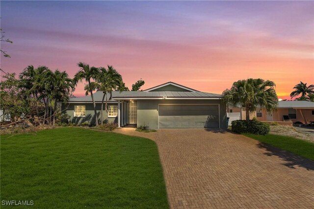 single story home featuring a garage and a yard