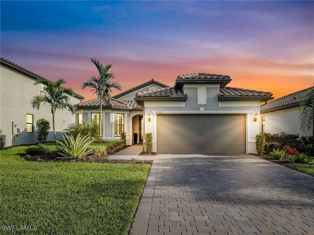 mediterranean / spanish-style house featuring a garage and a lawn