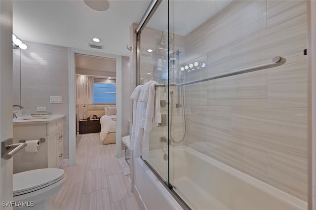 full bathroom featuring vanity, bath / shower combo with glass door, and toilet