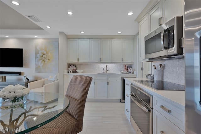 kitchen featuring white cabinets, appliances with stainless steel finishes, backsplash, and sink