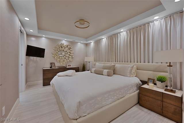 bedroom featuring light hardwood / wood-style floors and a tray ceiling