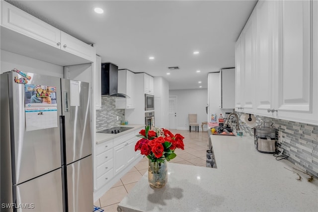 kitchen with stainless steel appliances, wall chimney range hood, white cabinets, decorative backsplash, and light tile patterned floors