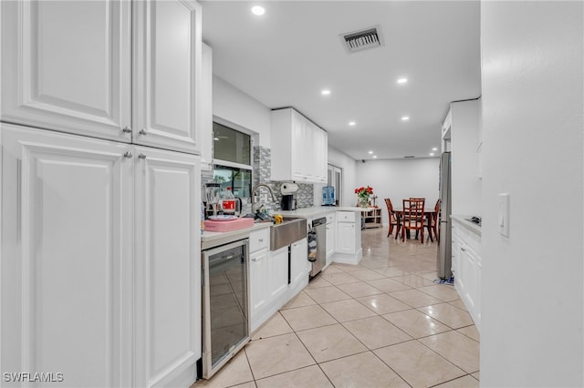 kitchen with white cabinets, light tile patterned floors, backsplash, and wine cooler