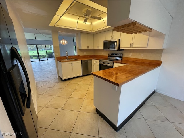 kitchen featuring white cabinets, stainless steel appliances, kitchen peninsula, and butcher block counters