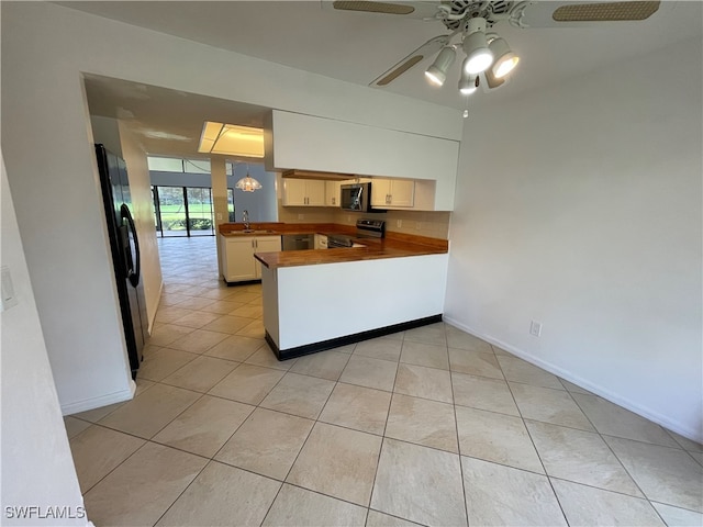 kitchen with ceiling fan, sink, kitchen peninsula, light tile patterned floors, and appliances with stainless steel finishes