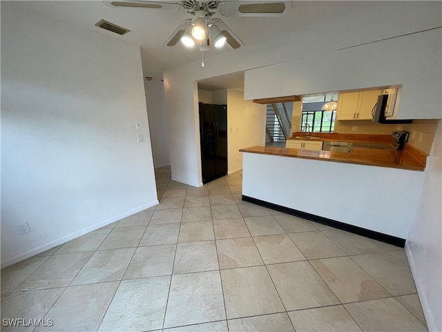 kitchen with ceiling fan, sink, black appliances, light tile patterned floors, and butcher block counters