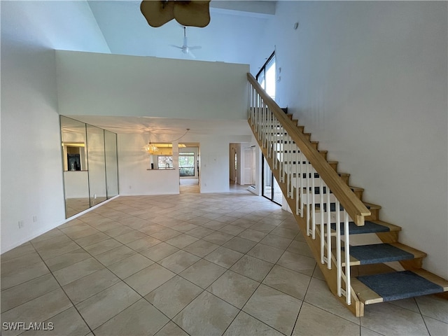 unfurnished living room with ceiling fan, light tile patterned flooring, and high vaulted ceiling