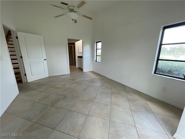 unfurnished room with ceiling fan, light tile patterned floors, and a high ceiling