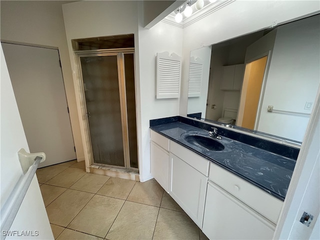 bathroom with tile patterned flooring, vanity, toilet, and a shower with shower door