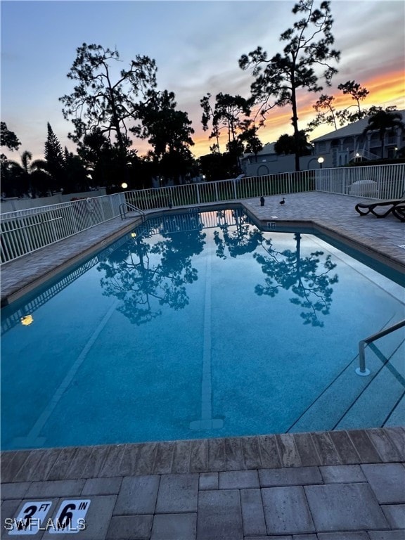 pool at dusk with a patio area