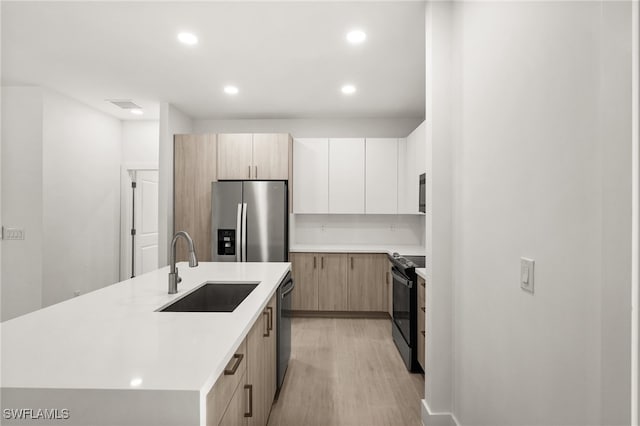 kitchen featuring a center island with sink, sink, light brown cabinetry, light hardwood / wood-style floors, and stainless steel appliances