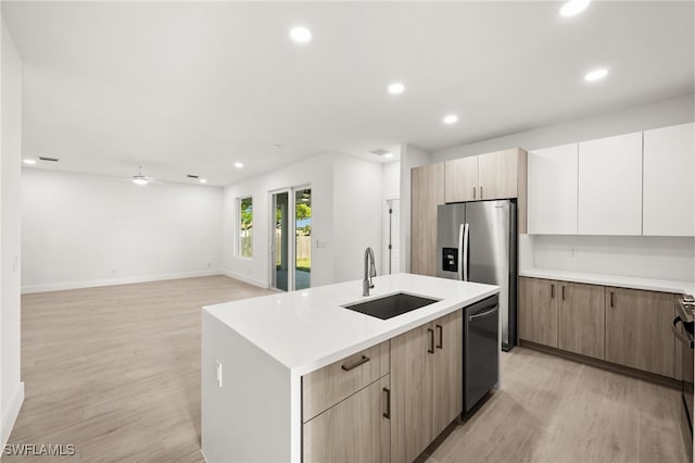 kitchen featuring sink, light brown cabinets, stainless steel appliances, light hardwood / wood-style flooring, and an island with sink