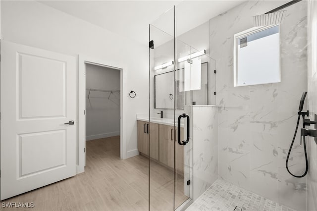 bathroom with hardwood / wood-style floors, vanity, and a shower with door