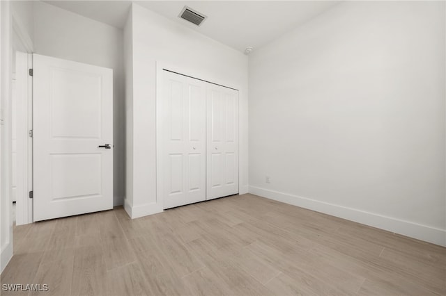 unfurnished bedroom featuring light hardwood / wood-style floors and a closet