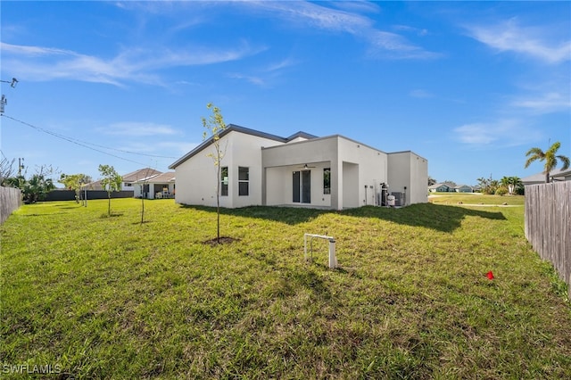 rear view of property with a lawn and ceiling fan