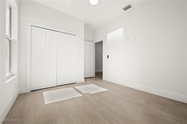 unfurnished bedroom featuring light wood-type flooring and a closet