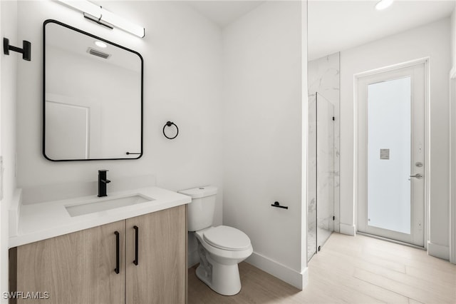 bathroom featuring walk in shower, toilet, vanity, and hardwood / wood-style flooring