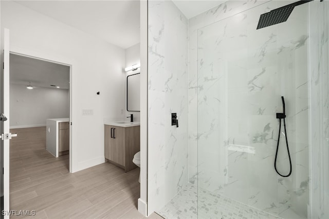 bathroom featuring tiled shower, toilet, vanity, and hardwood / wood-style flooring